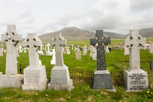 Barra cemetery with a close view of 5 prominent celtic cross engraved graves facing the sea. All the other graves face the land.