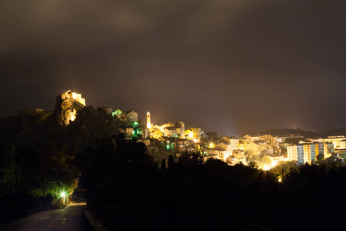 Photo of Corte castle taken at night showing the village and castle illuminated.