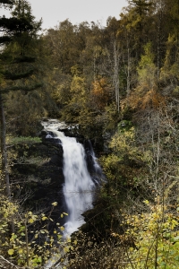 Large waterfall cascading seen across the valley from the path at Birks of Aberfeldy.